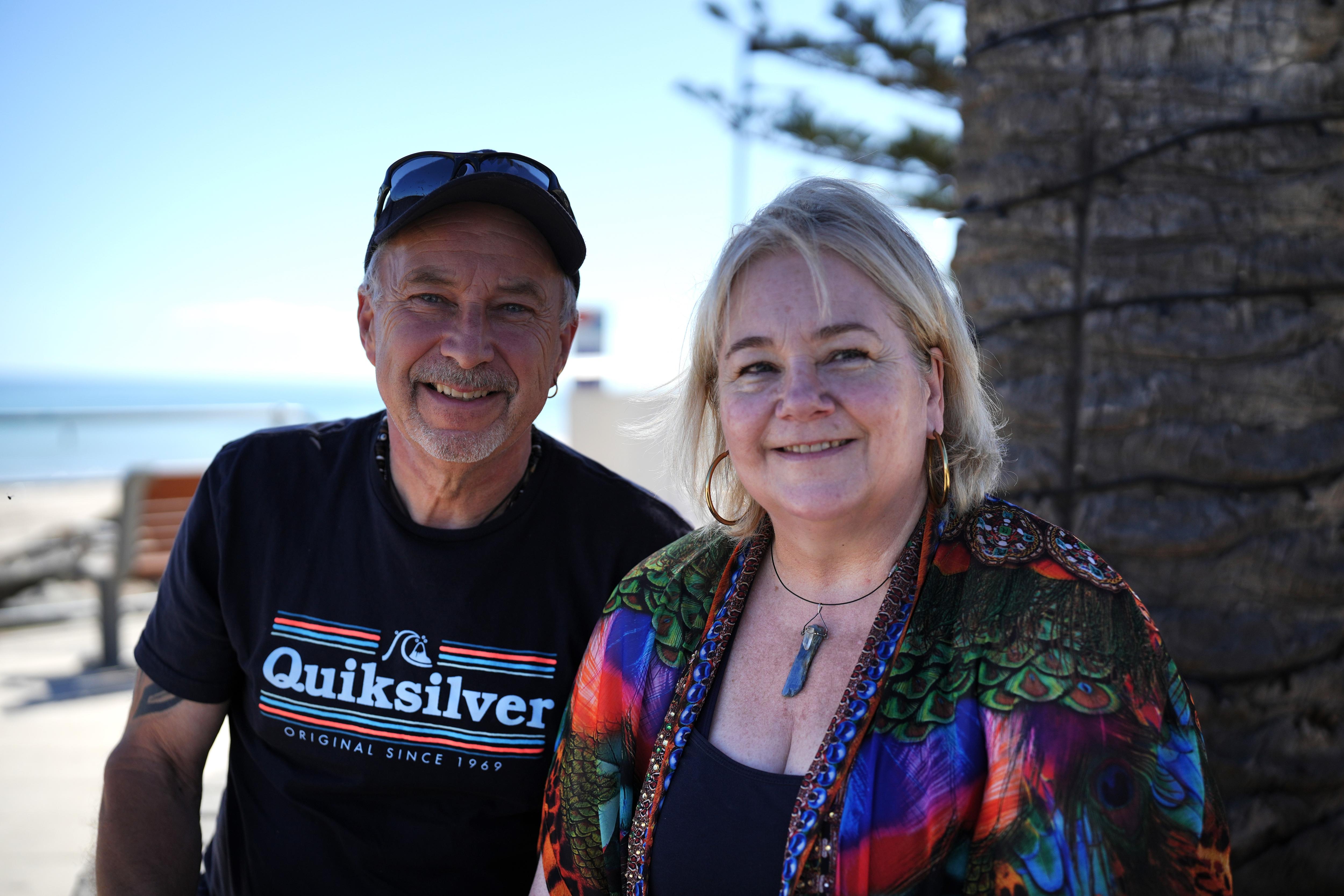 Un hombre y una mujer sonreen para una fotografía en una playa suburbana