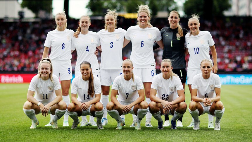Women soccer players wearing white pose for a photo