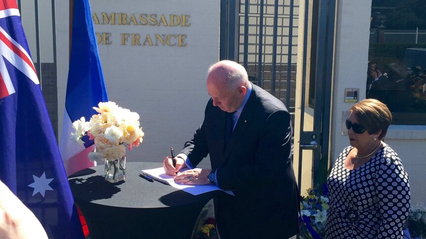 Governor-General Sir Peter Cosgrove signing the condolence book outside the French Embassy.