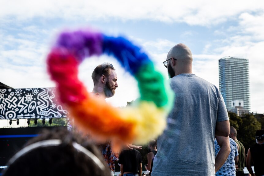 A rainbow-coloured ring forms a frame around a bearded man's face