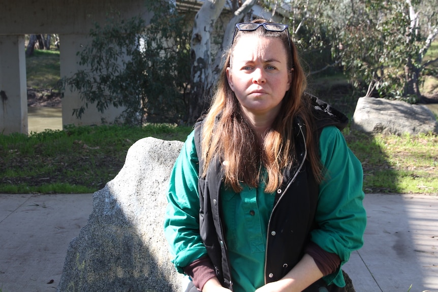 A woman stares at the camera with a plain expression.