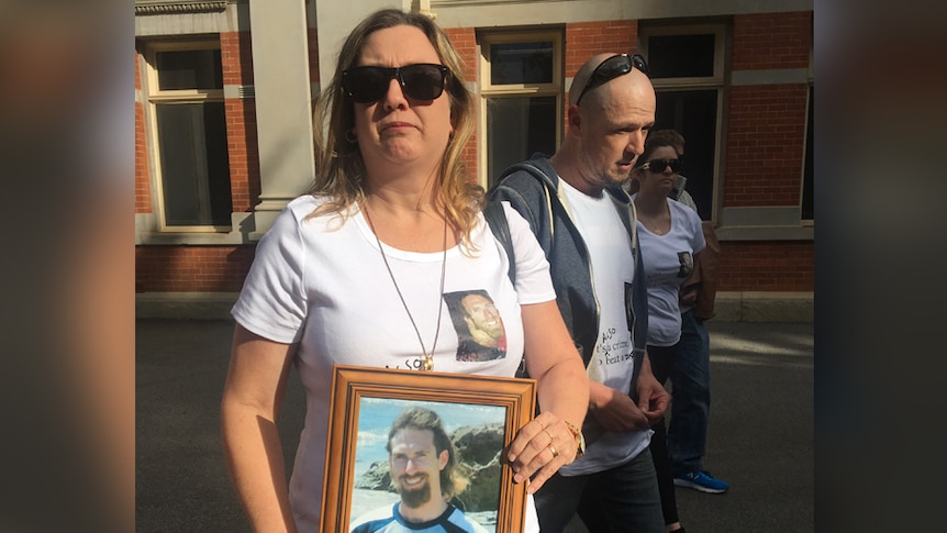 Two women and a man hold a photo of a young man outside the Perth Supreme Court.