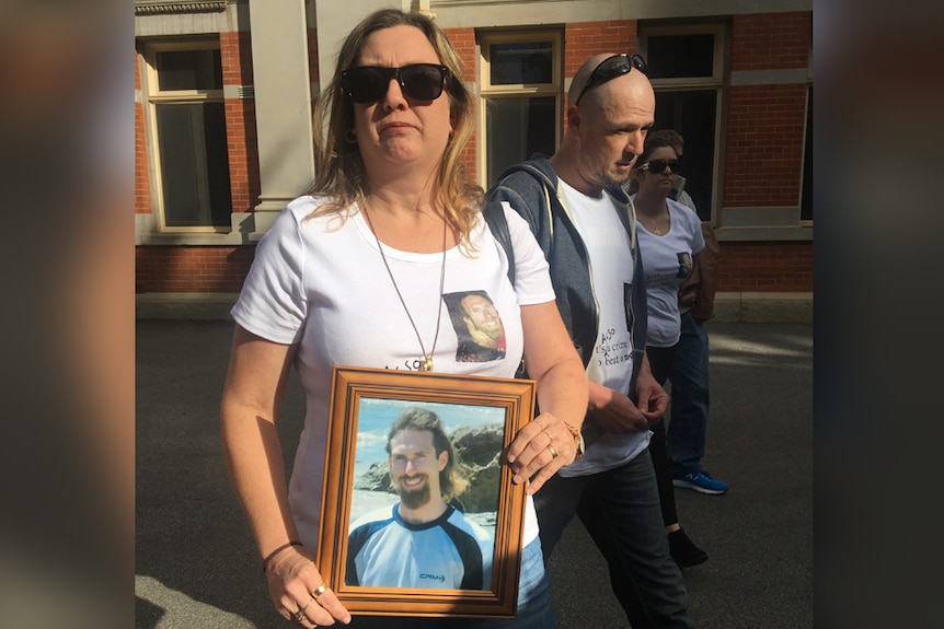 Two women and a man hold a photo of a young man outside the Perth Supreme Court.