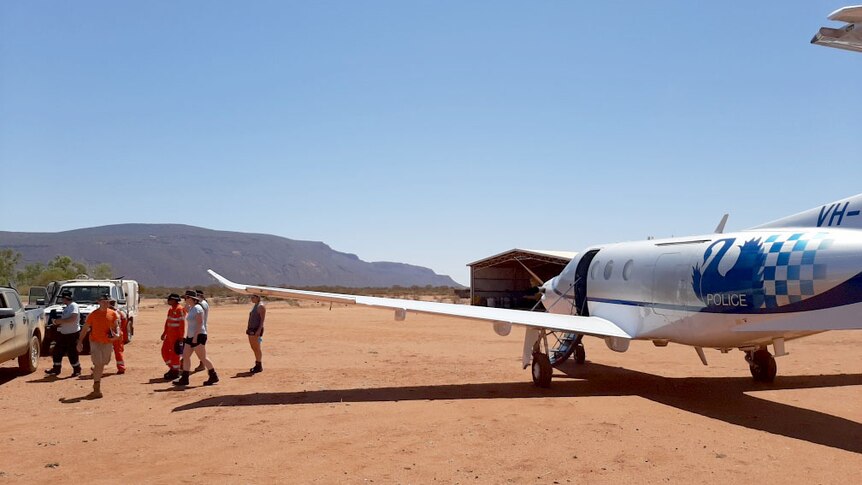 A police plane on a red dirt air strip with Mt Augustus in the background.