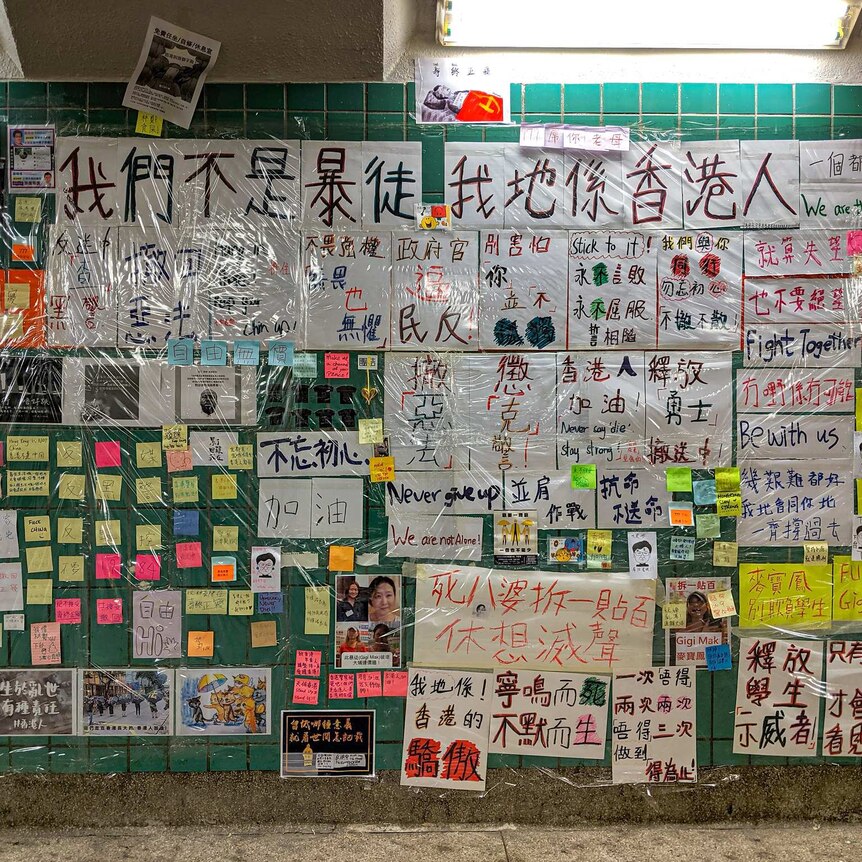 A wall plastered with sticky notes, posters and photos, with Chinese and English writing visible