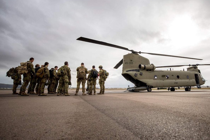 Australian soldiers from Townsville's 3rd-Brigade stand next to a Chinook helicopter.