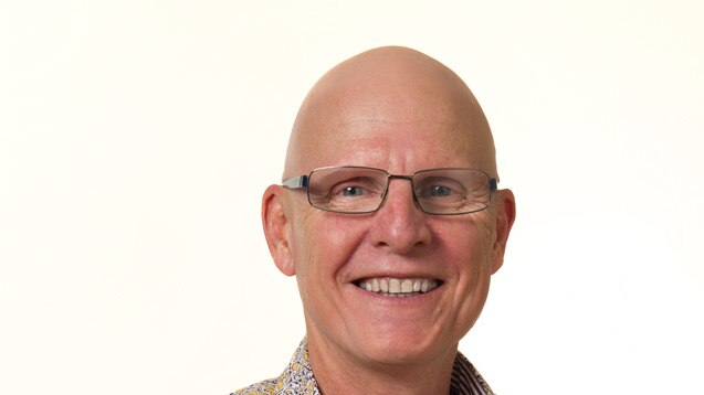 Bald man in glasses smiles at camera