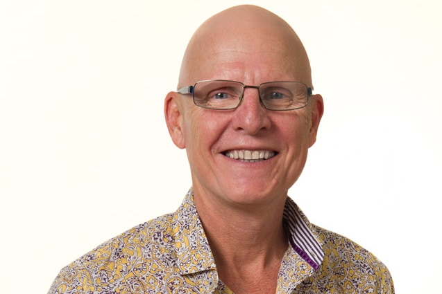 Bald man in glasses smiles at camera