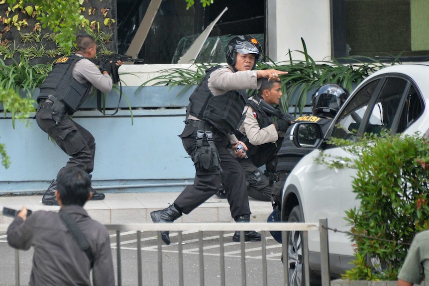 Indonesian police take position and aim handguns at suspects inside Starbucks after series of explosions in Jakarata, Indonesia January 14, 2016