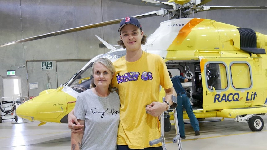 Melita Carlyon and Ned Desbrow stand in front of a rescue helicopter.