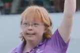 A teenage golfer with Down's Syndrome waves at the crowd on the 16th green at TPC Scottsdale.