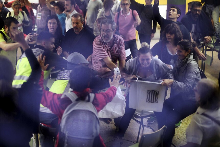 Spanish National Police officers in plain clothes and voters clash as they try to snatch a ballot box