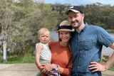 Leonie and her husband smiling while standing outside, in a story about pressure to buy property.