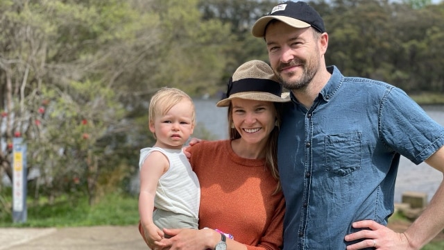 Leonie and her husband smiling while standing outside, in a story about pressure to buy property.