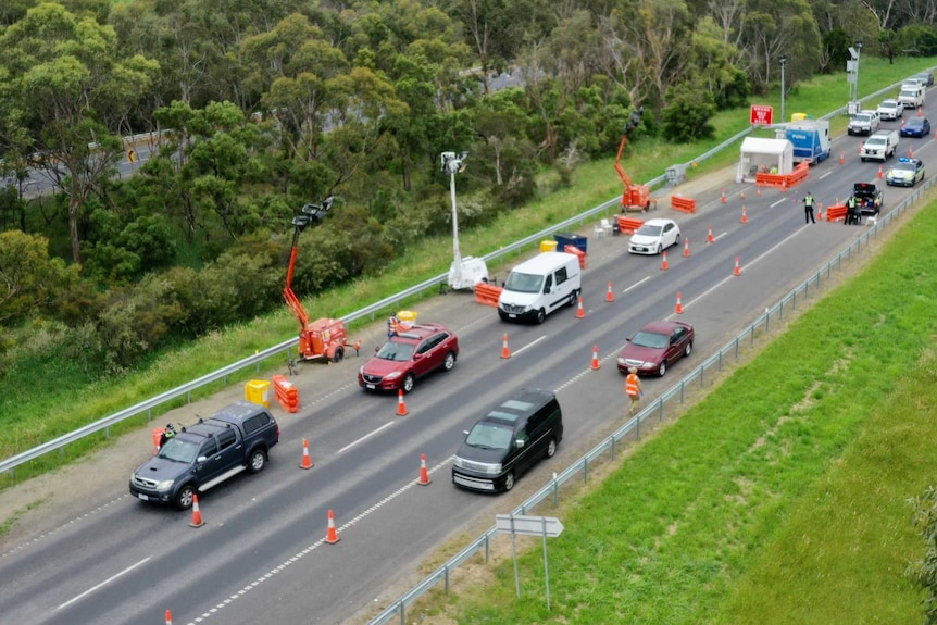 An elevated view of a police checkpoint with stationary cars on a highway.