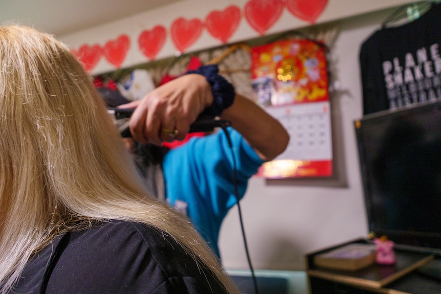 A woman doing another woman's hair.