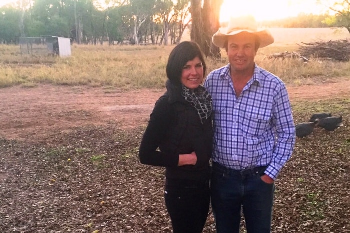 Kate and Justin Boshammer standing in front of a Eucalypt tree with the setting sun behind it