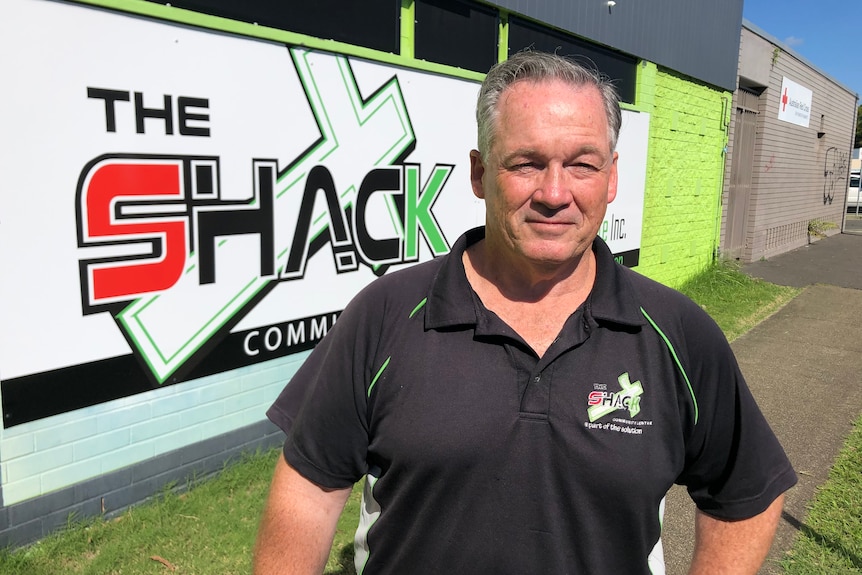 Man stands in front of The Shack community centre sign on the side of a building