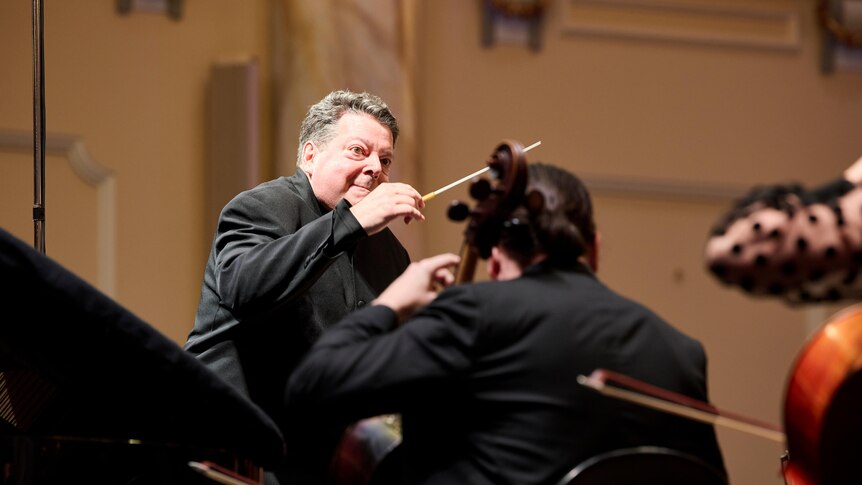 Andrew Litton is conducting the ASO, with an intense expression of concentration on his face.
