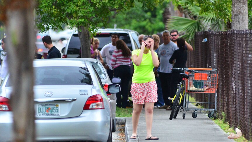 People stand outside a Florida apartment building after a shooting incident