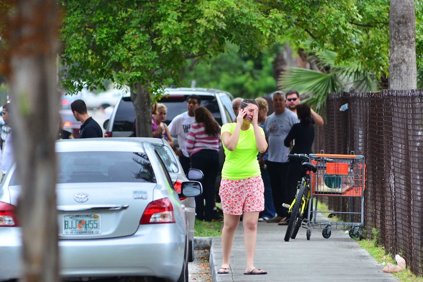 People stand outside a Florida apartment building after a shooting incident