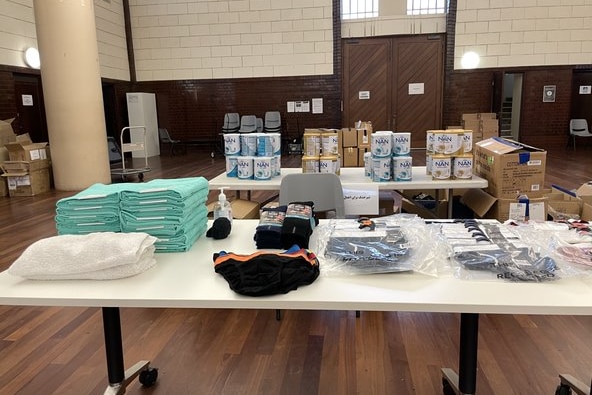A table with donated items ready for newly arrived evacuees, including baby formula, and clothes. 