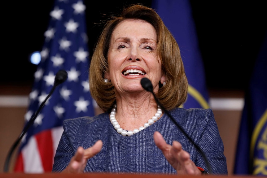 Nancy Pelosi speaks and makes a hand gesture at a lectern