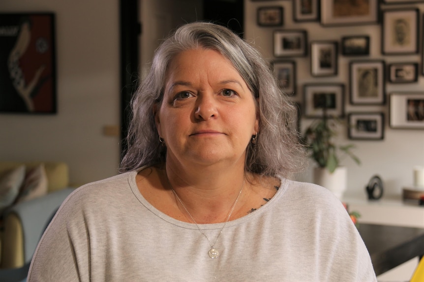 A woman with gray hair looks at the camera 
