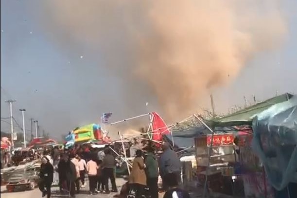 A market place in chao as people run before an oncoming dust devil.