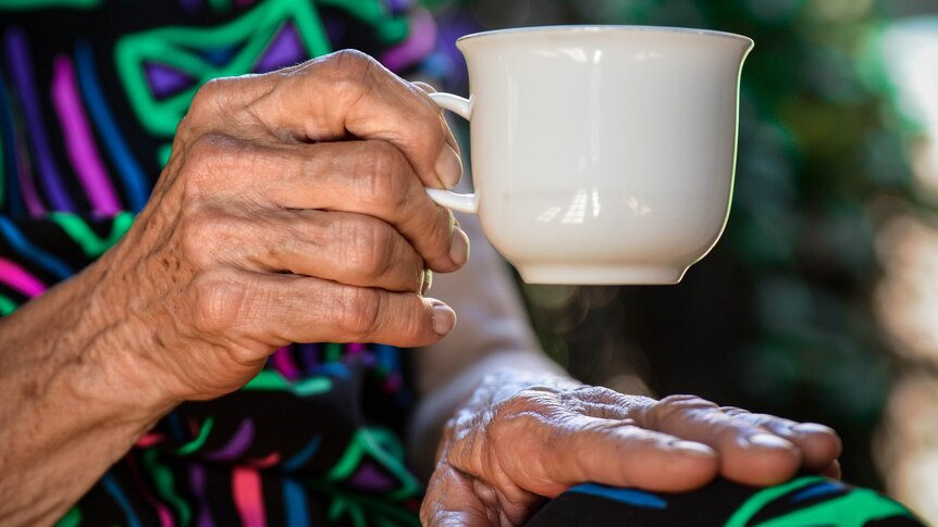 An elderly woman holding a tea cup