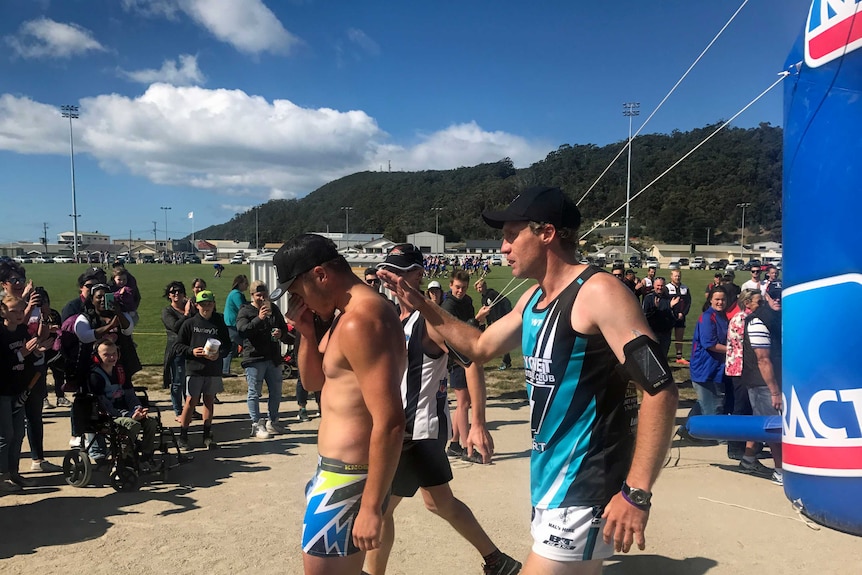 Brayden Hayes is congratulated after crossing the finishing line in Burnie. He ran 323 kilometres in his underpants after losing a bet.