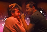Paul Mescal and Andrew Scott look lovingly into each other's eyes while in bed, fully clothed.