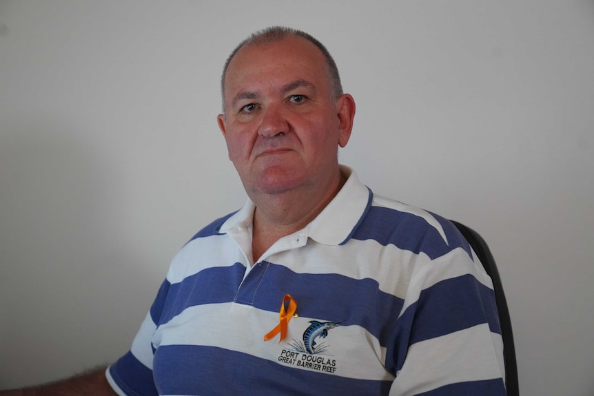 A middle-aged man wearing a blue and white striped shirt.