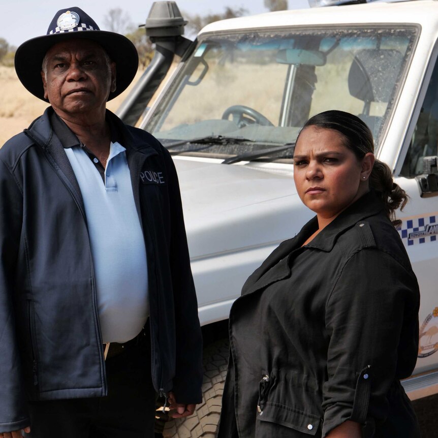 actors warren Hi Williams in police uniform and Rarriwuy hick in front of a police wagon
