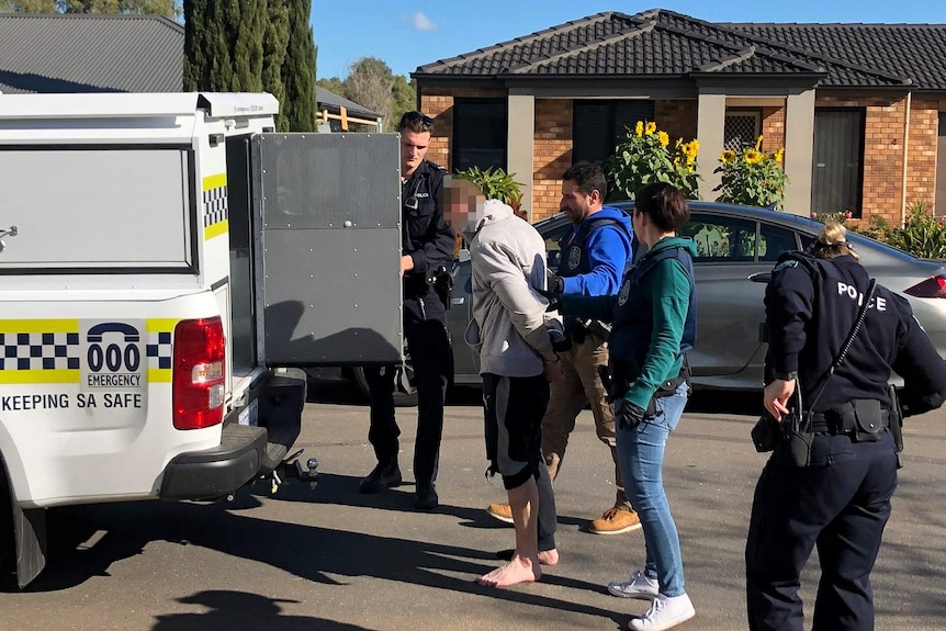 A suspect is taken into a police van.