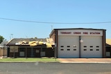 A building with sign saying Tennant Creek Fire Station with with insulation falling off the roof.