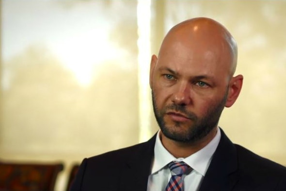 A mid-shot of a seated man in an interview