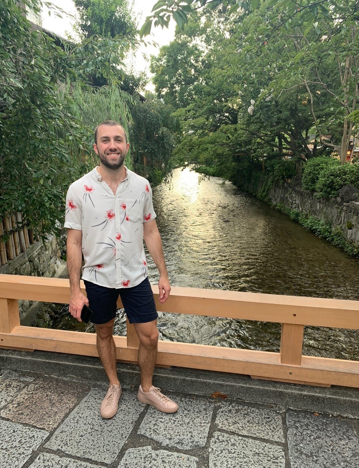 Jake Wheeler posed for a photo on a bridge overlooking a river.