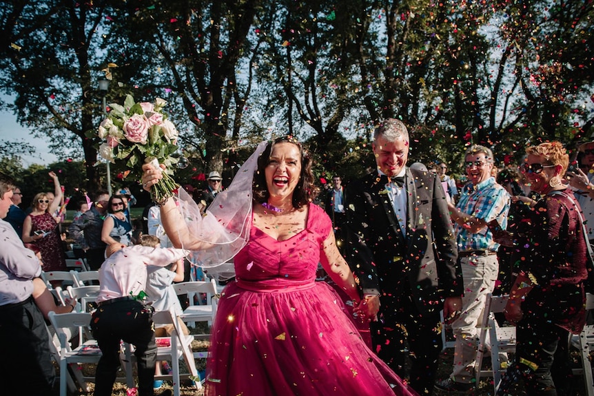 Catherine Deveny and her partner walk through confetti after their Love Party ceremony.