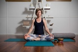 Hannah Perkins sitting cross-legged in a yoga studio.
