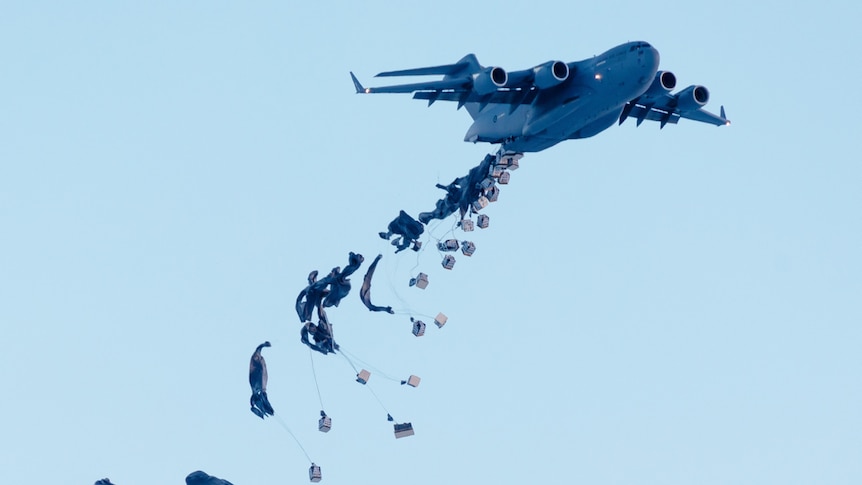 A defence force plan dropping goods from its cargo hold.