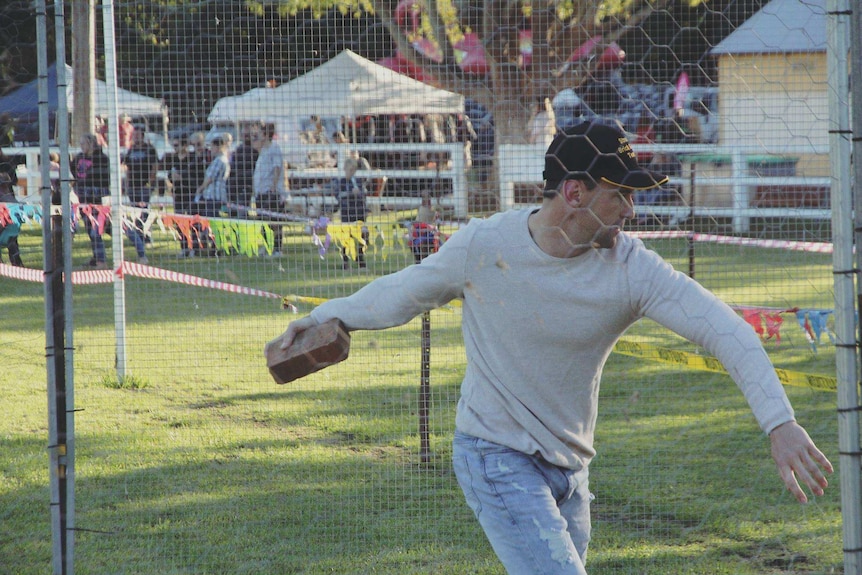 man spinning as he prepares to throw a brick