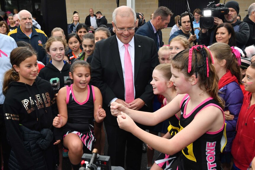 Prime Minister Scott Morrison joins a group of netball players in a chant.