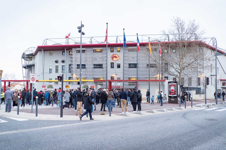 People stand outside a small stadium.
