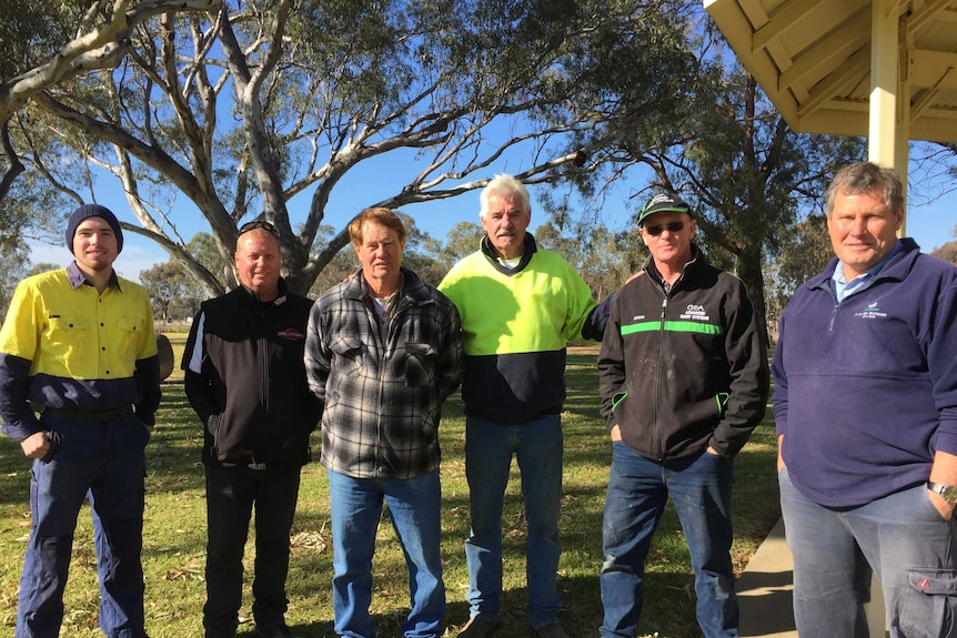 Men stand in a group under gum trees at Numurkah in northern Victoria.