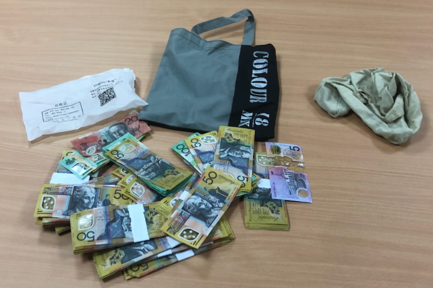 bundles of cash, grey bag and white pouch with Chinese writing
