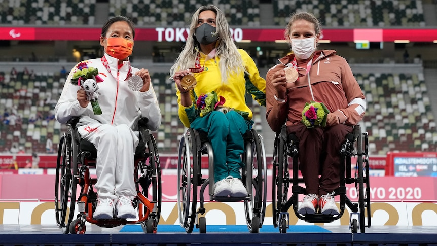 Three female Paralympic wheelchair athletes on the medal podium together in Tokyo.