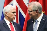 Mike Pence speaks to Scott Morrison while standing in front of national flags.