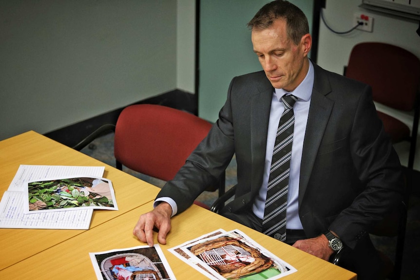 Detective David Nicoll looks at photos on a table