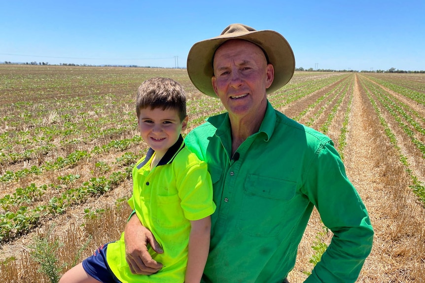 Rob Houghton and his grandson Boston kneeling in a mung bean crop at Gogeldrie in southern New South Wales